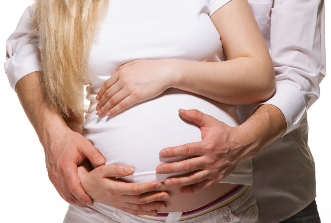 Pregnant woman holding belly while saying birth mantras