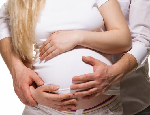 Pregnant woman holding belly while saying birth mantras