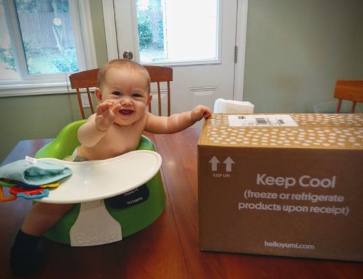 Baby sits by box of yumi brand baby food for a yumi review